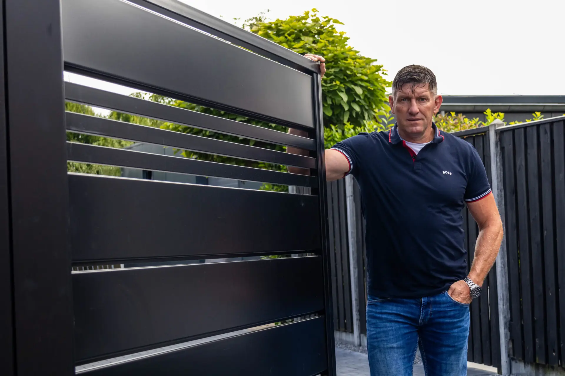 Patrick Spap&eacute; bij een moderne zwarte lamellenpoort